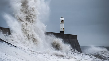 Large waves crashing against a coastal lighthouse during stormy weather
