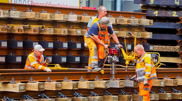 Rail maintenance workers handling track components