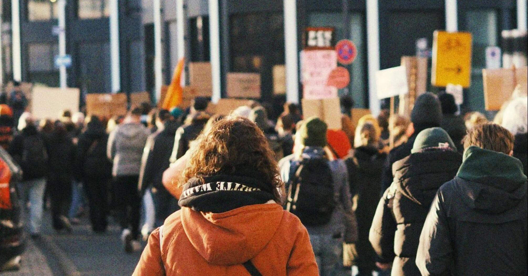 People marching in a protest with banners and signs in a city street