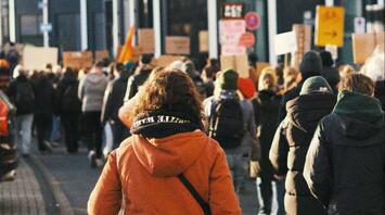 People marching in a protest with banners and signs in a city street