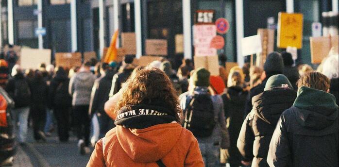 People marching in a protest with banners and signs in a city street