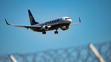 Ryanair aircraft approaching for landing against clear blue sky
