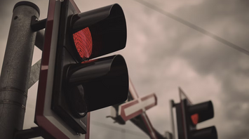 Red railway crossing lights against cloudy sky