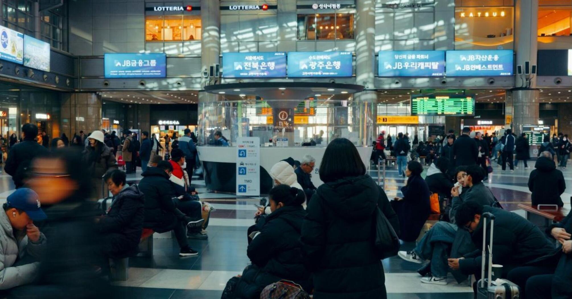 Passengers waiting with luggage inside a busy modern airport terminal