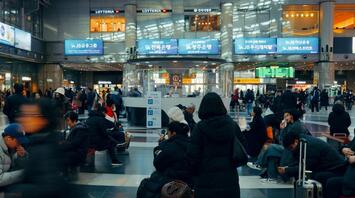 Passengers waiting with luggage inside a busy modern airport terminal