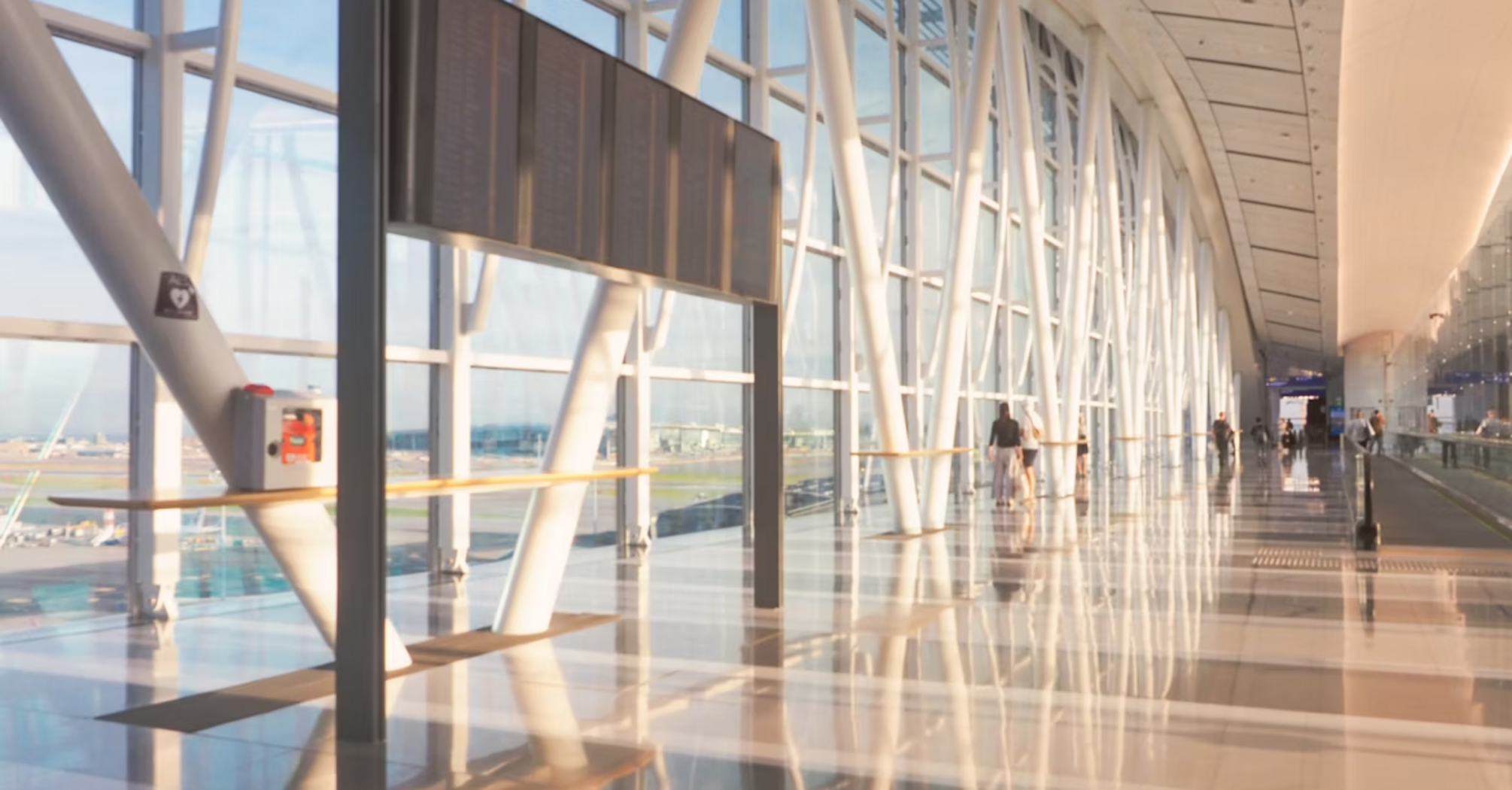 Modern airport terminal corridor with passengers walking and large flight information board
