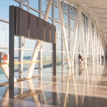 Modern airport terminal corridor with passengers walking and large flight information board