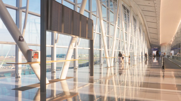 Modern airport terminal corridor with passengers walking and large flight information board