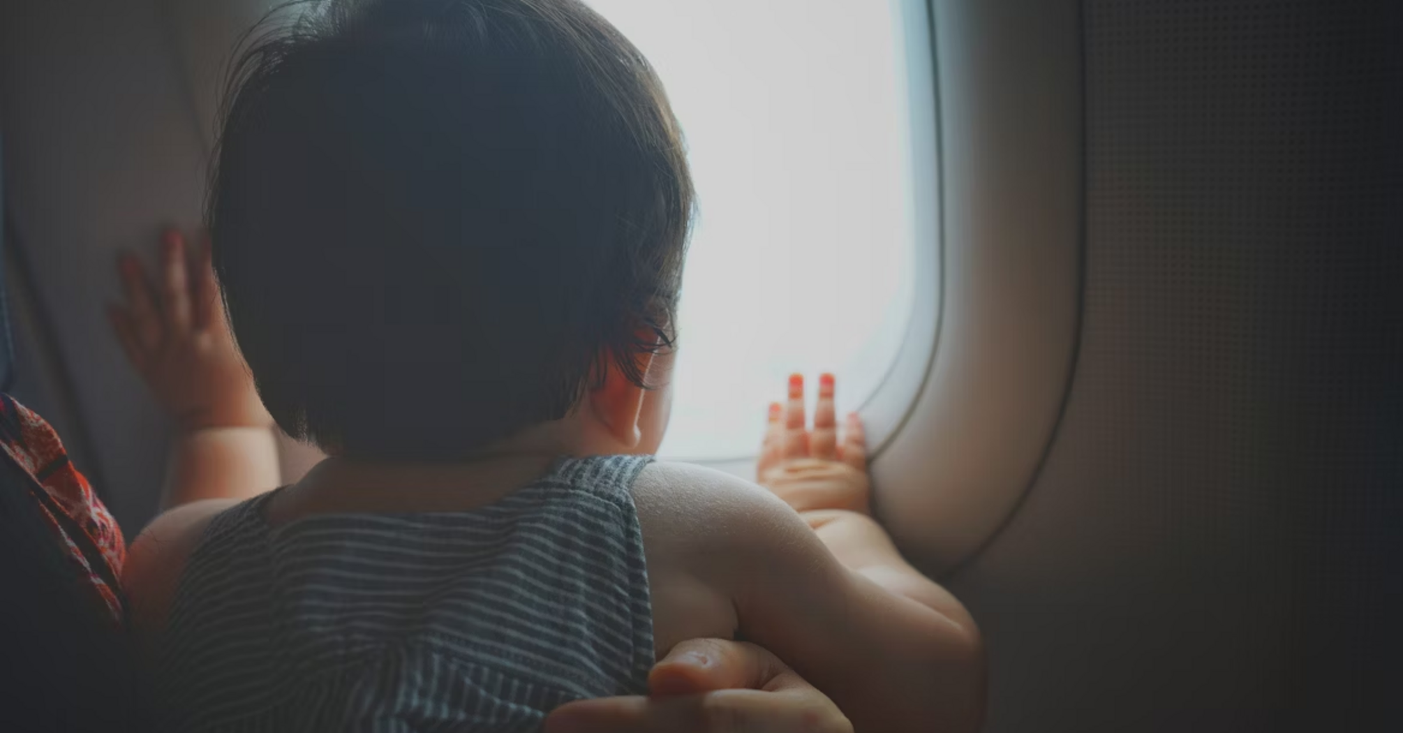 Infant looking out airplane window during flight