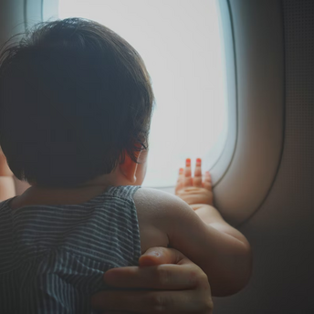 Infant looking out airplane window during flight