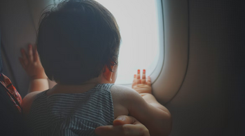 Infant looking out airplane window during flight