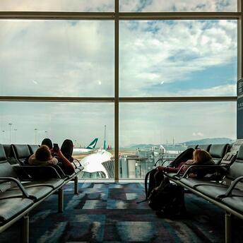 Passengers waiting in airport lounge with planes outside