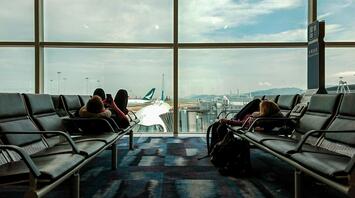 Passengers waiting in airport lounge with planes outside