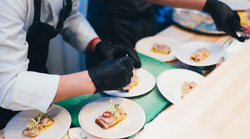 Chefs preparing plated regional dishes at an event