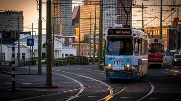 Tram on city tracks at sunset with tall buildings in the background