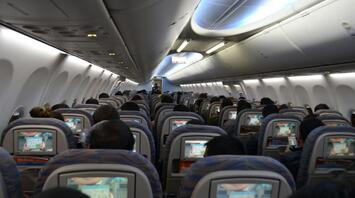 Passengers seated inside an airplane cabin with in-flight screens