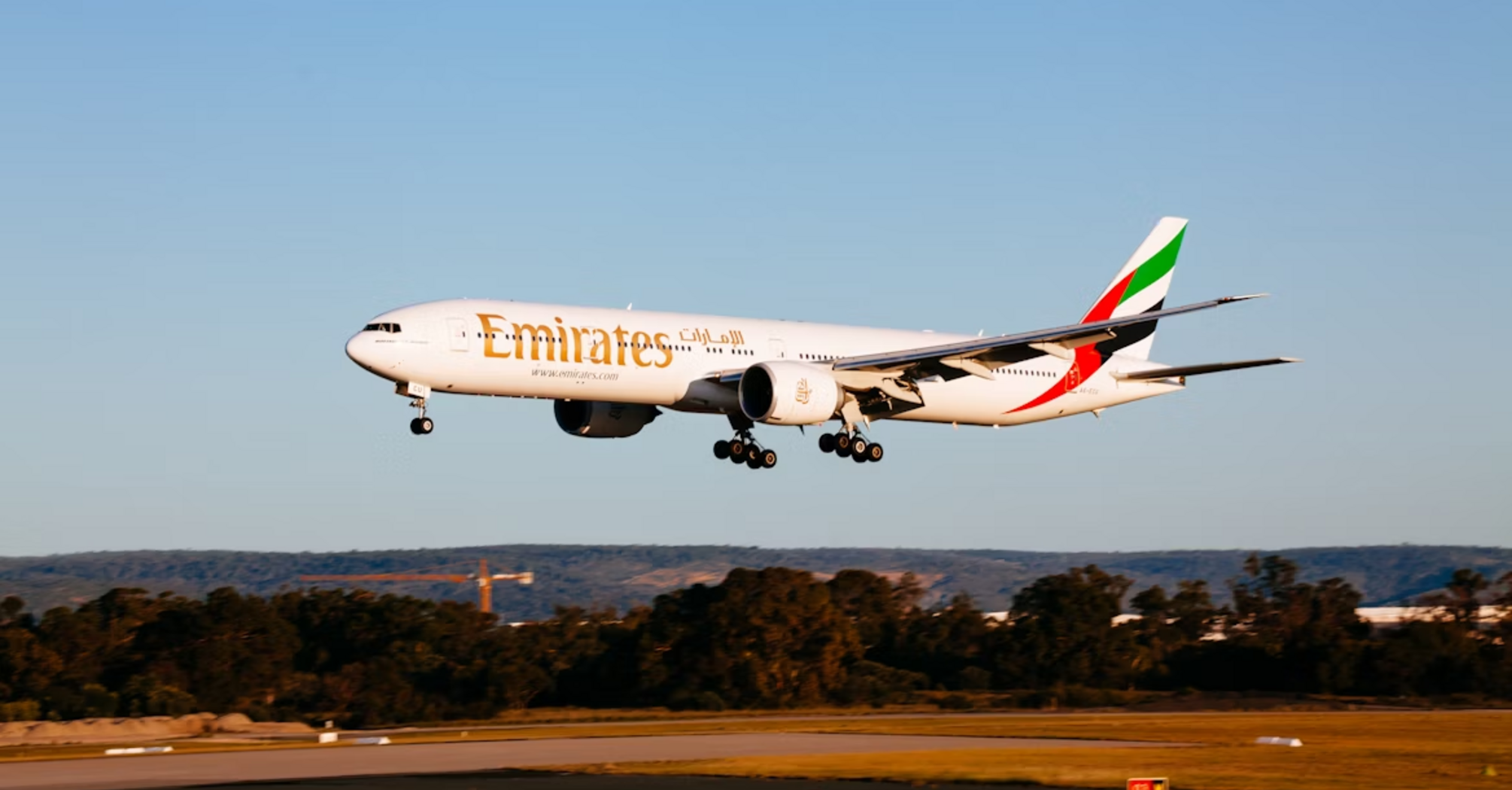 Emirates airplane preparing to land on runway during sunset