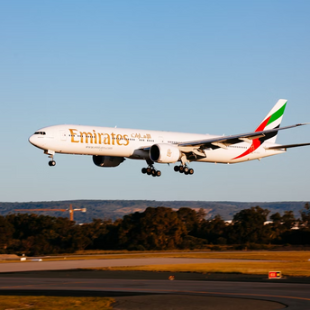 Emirates airplane preparing to land on runway during sunset