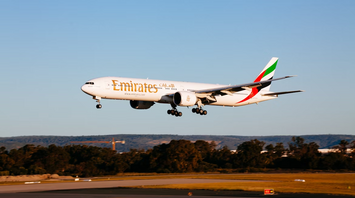 Emirates airplane preparing to land on runway during sunset