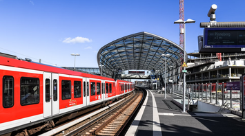 Red regional train at a modern glass-covered station platform in Germany