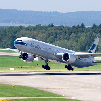 Cathay Pacific aircraft taking off from a runway surrounded by greenery