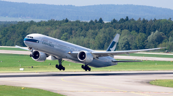 Cathay Pacific aircraft taking off from a runway surrounded by greenery