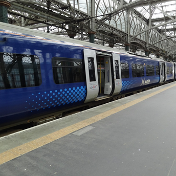 ScotRail train at a station platform under a large glass roof