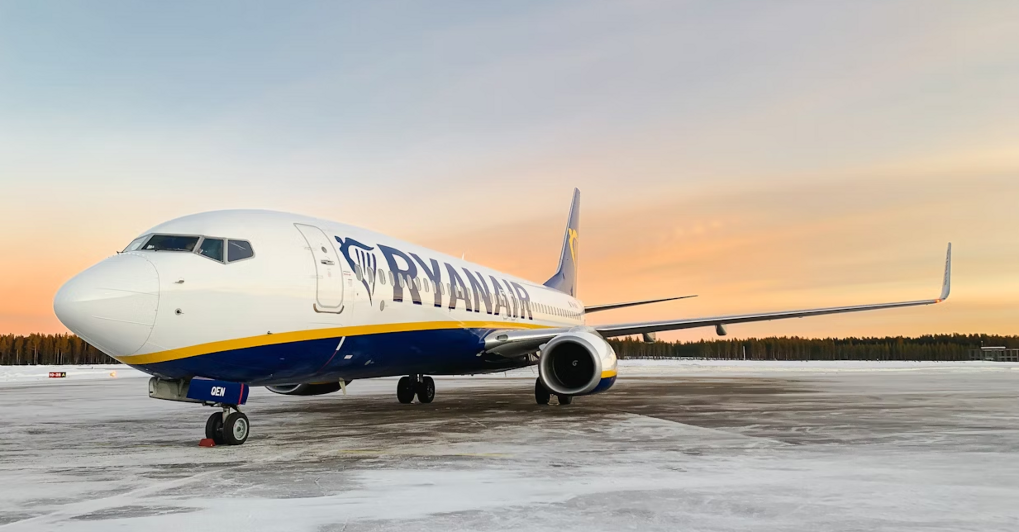 Ryanair aircraft on a snowy runway at sunset
