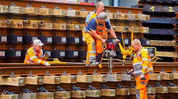 Railway workers in high-visibility clothing conducting track maintenance