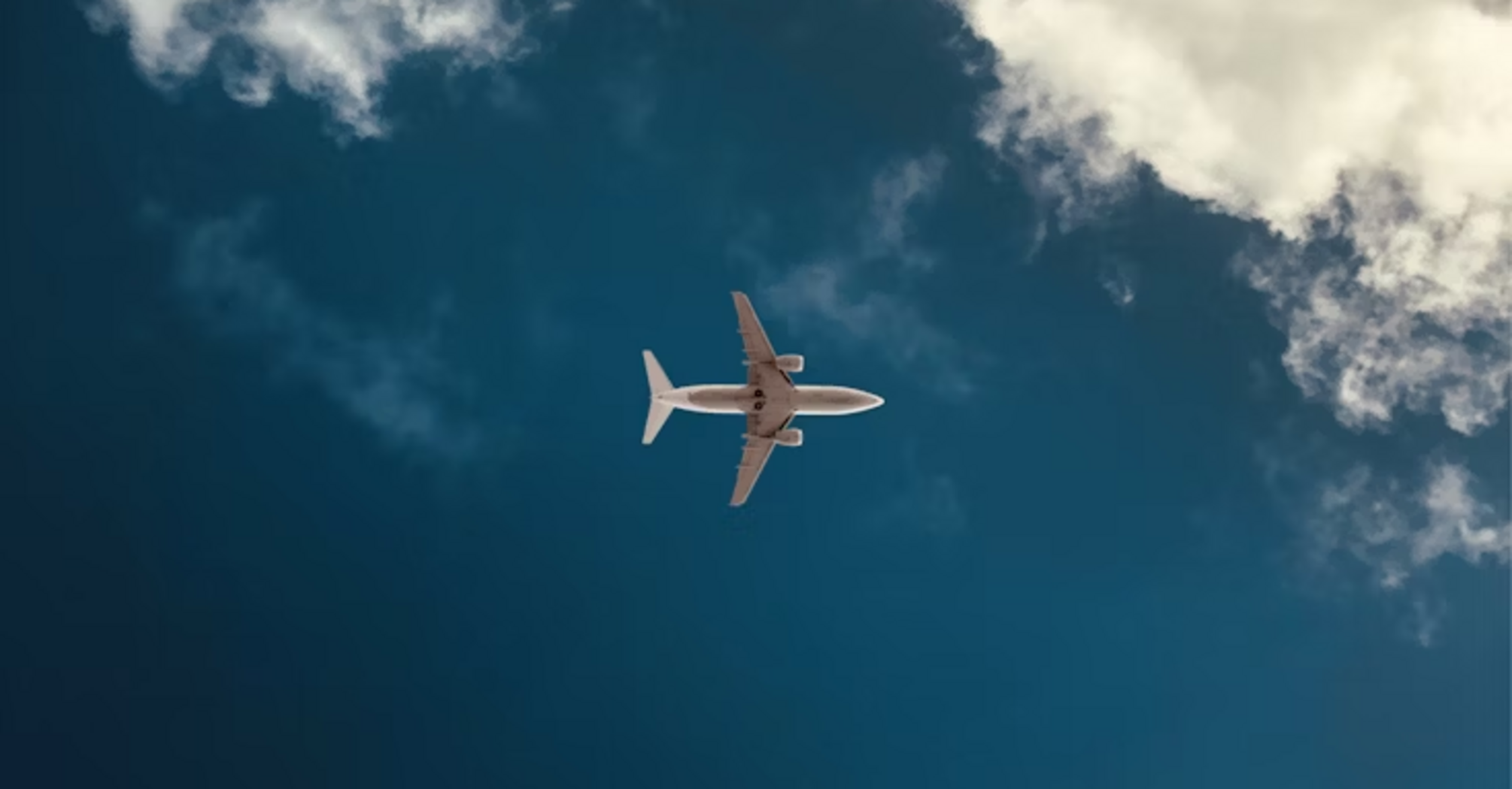 Airplane flying through clear sky with clouds