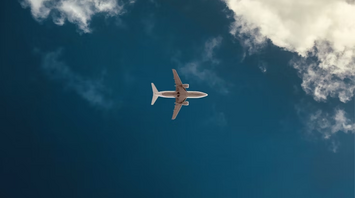Airplane flying through clear sky with clouds