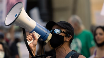 Woman wearing a mask speaks into a megaphone during a public protest