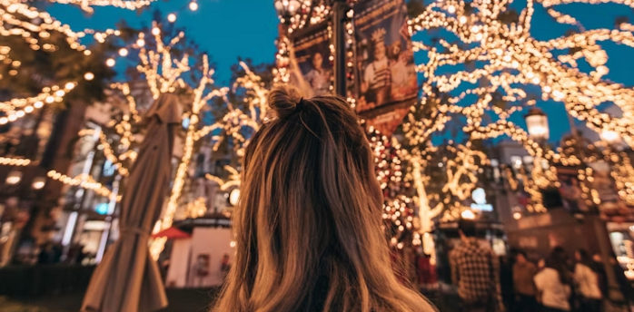 A person admiring festive lights illuminating a European city street in November