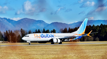 flydubai aircraft taxiing on runway with mountains in the background