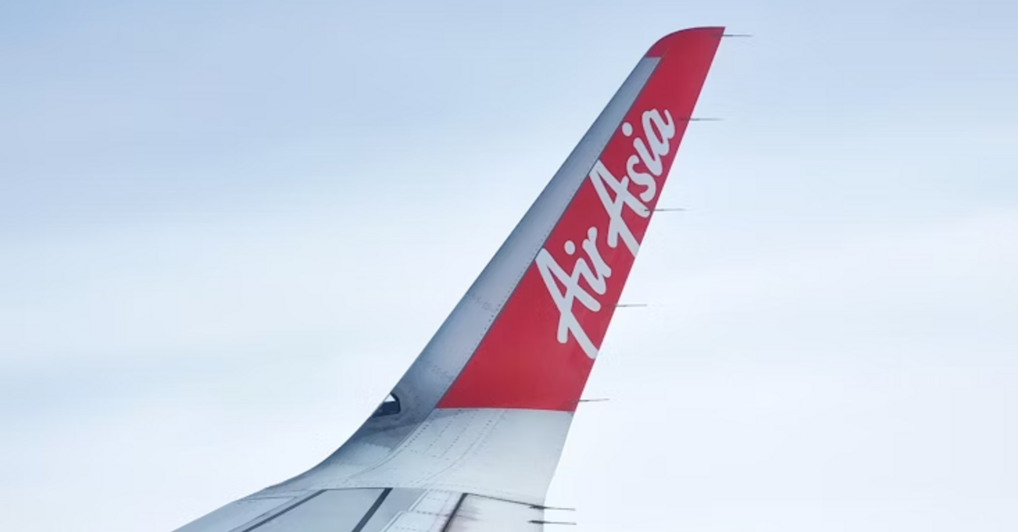 AirAsia airplane wing and logo above the clouds