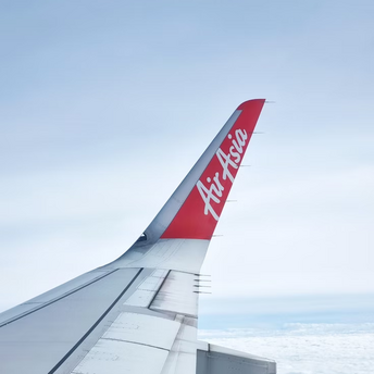 AirAsia airplane wing and logo above the clouds