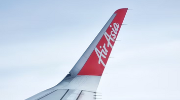 AirAsia airplane wing and logo above the clouds