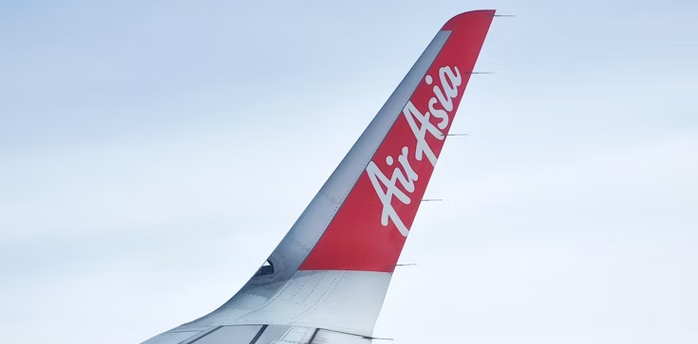 AirAsia airplane wing and logo above the clouds
