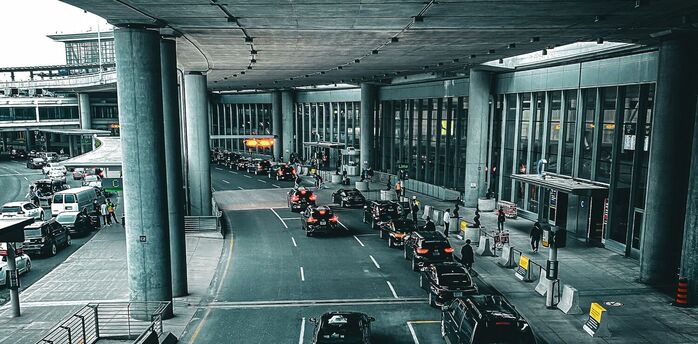 Cars lining up outside Berlin Brandenburg Airport terminal under a covered roadway