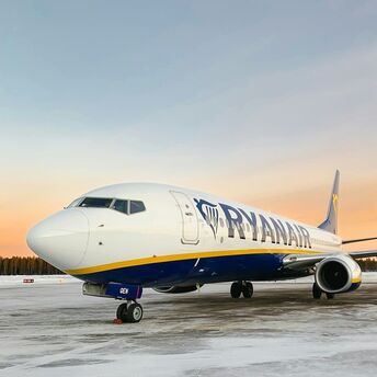 Ryanair plane on snowy runway at sunrise