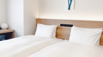 Modern hotel room with twin beds and minimal decor