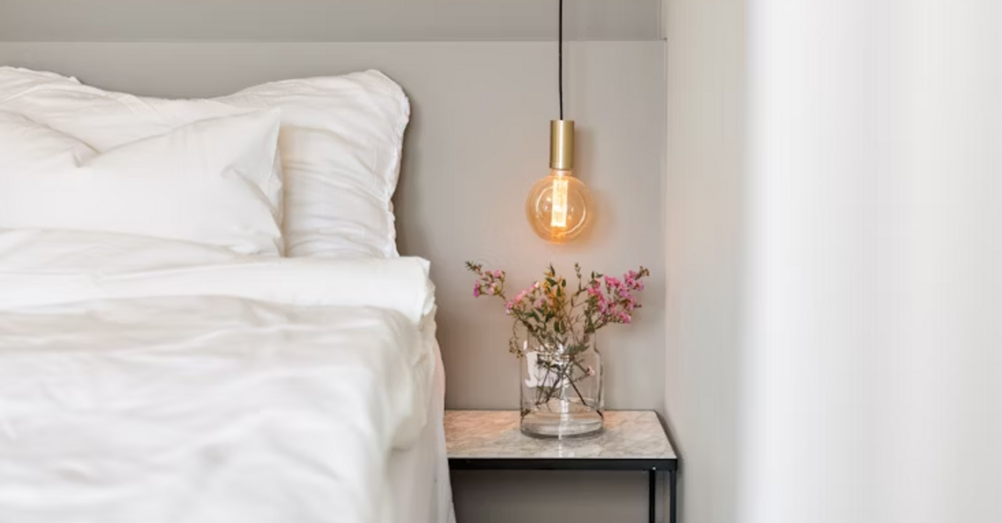 Modern hotel bedroom corner with bedside table and hanging light