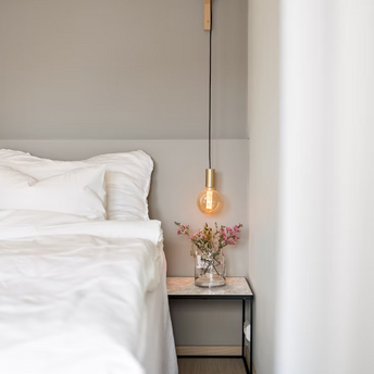 Modern hotel bedroom corner with bedside table and hanging light