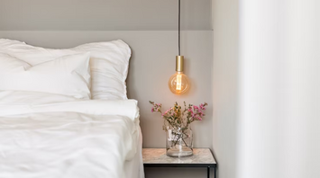Modern hotel bedroom corner with bedside table and hanging light
