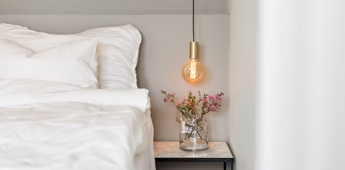 Modern hotel bedroom corner with bedside table and hanging light