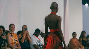 Model walking runway in flowing red gown