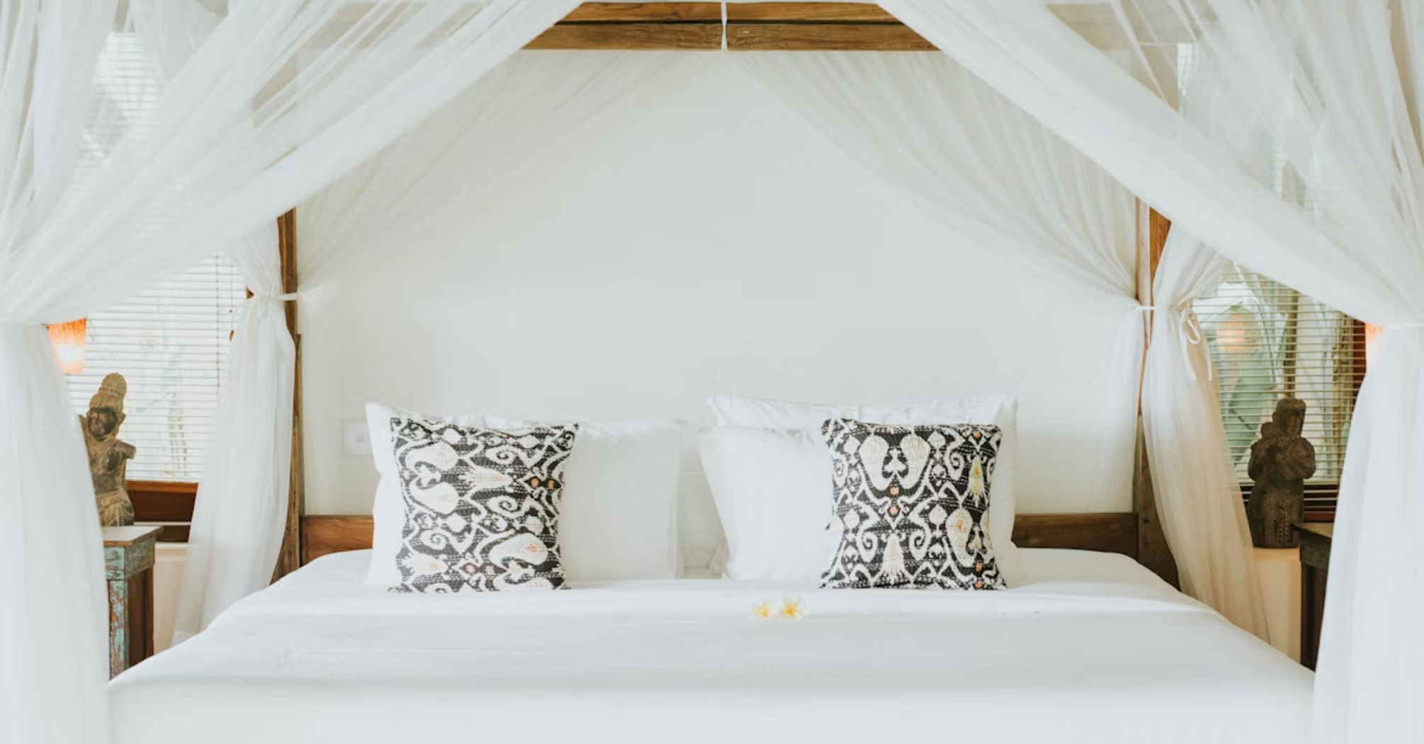 Elegant canopy bed with patterned pillows in a luxury resort room