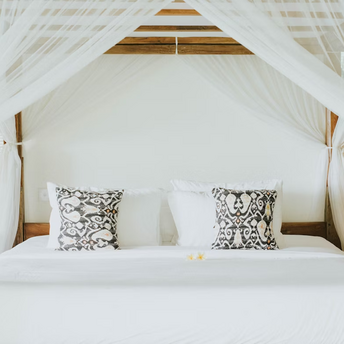Elegant canopy bed with patterned pillows in a luxury resort room