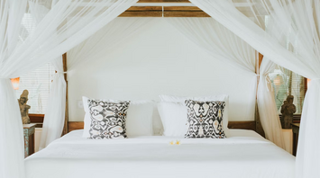 Elegant canopy bed with patterned pillows in a luxury resort room