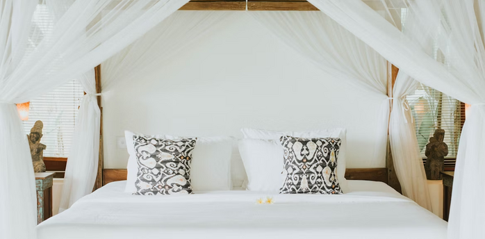 Elegant canopy bed with patterned pillows in a luxury resort room